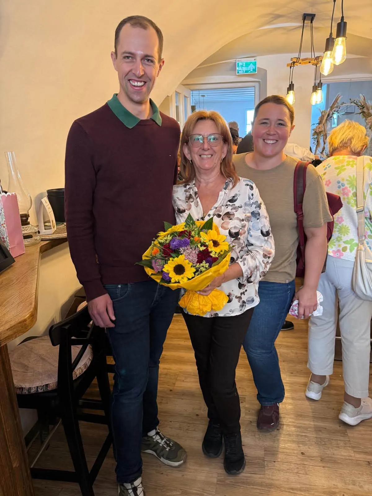 Drei Personen mit Blumenstrau&szlig; bei der Er&ouml;ffnungsfeier